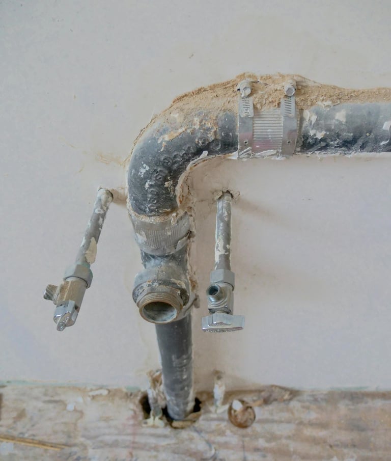 Préparation des arrivées d’eau et évacuation en attente pour lavabo, avec tuyaux et vannes apparente