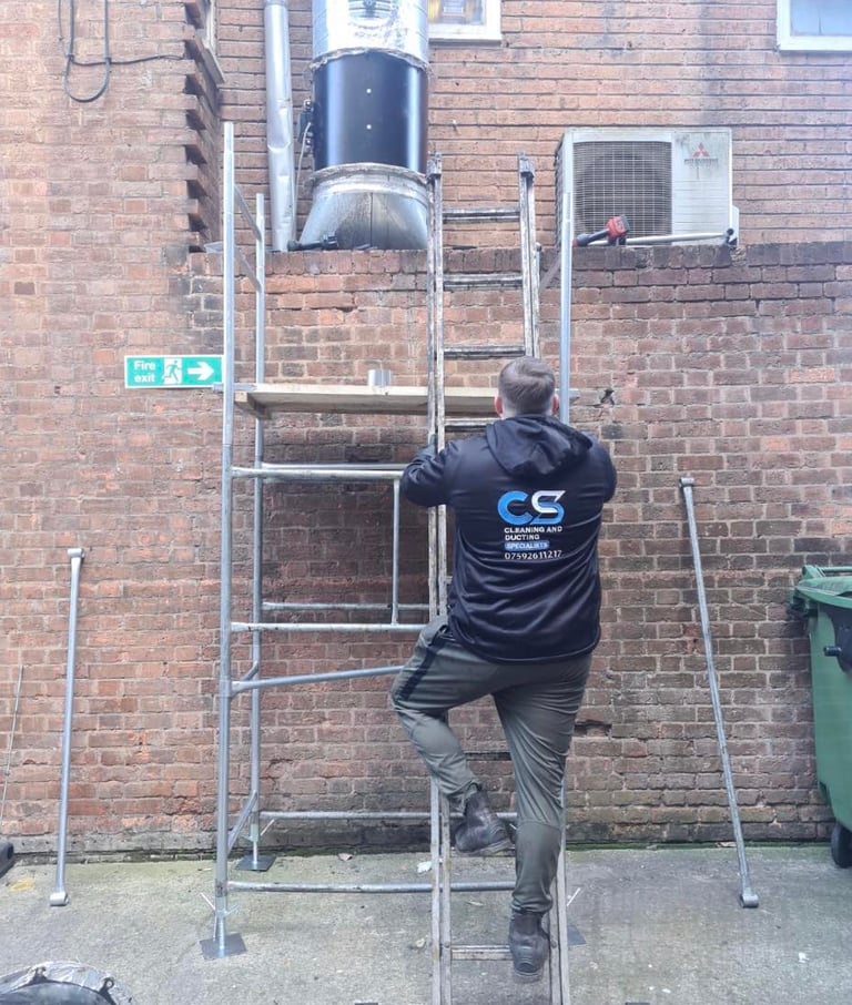 a man in cs cleaning and ducting company  workwear  fixing ducting