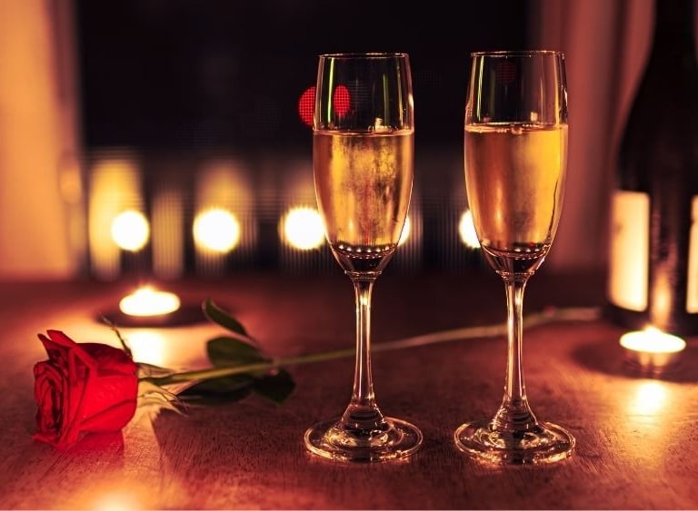 two champagne glasses with a rose on a table