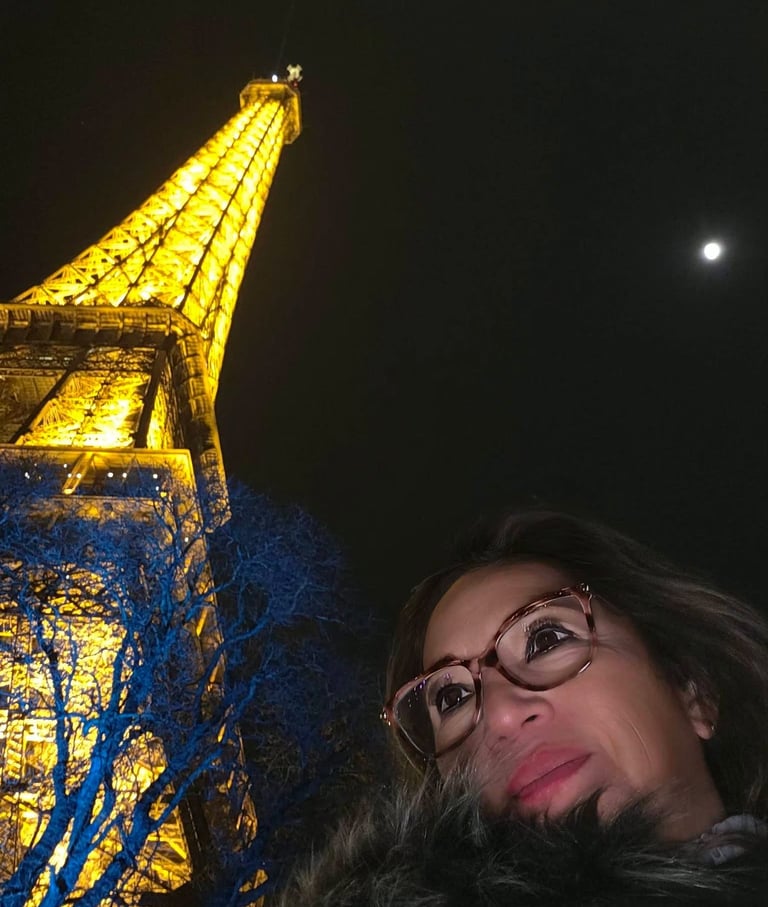 Mujer se toma una selfie frente a la Torre Eiffel iluminada por la noche en París. 