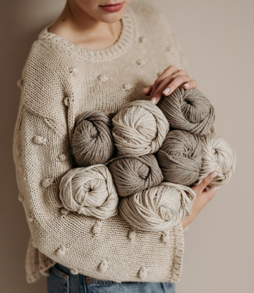 Pelotes de laine dans les bras d'une femme qui fait du crochet