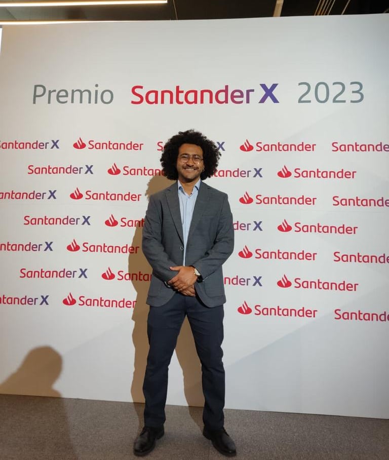 a man in a suit and tie standing in front of a sign that says,