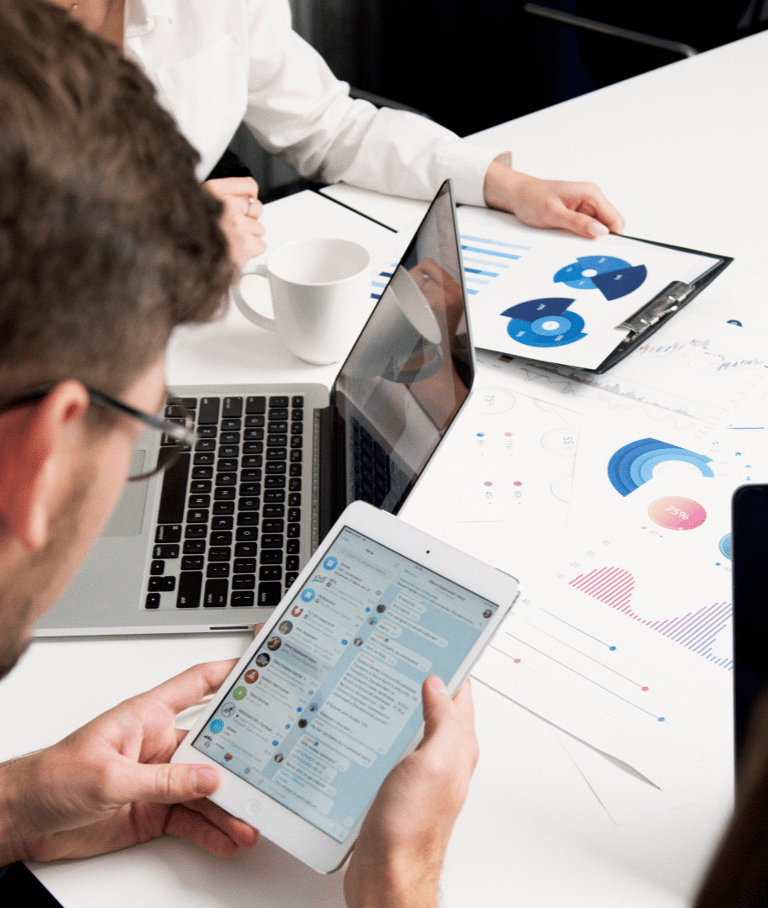 a man and woman sitting at a table with laptops 