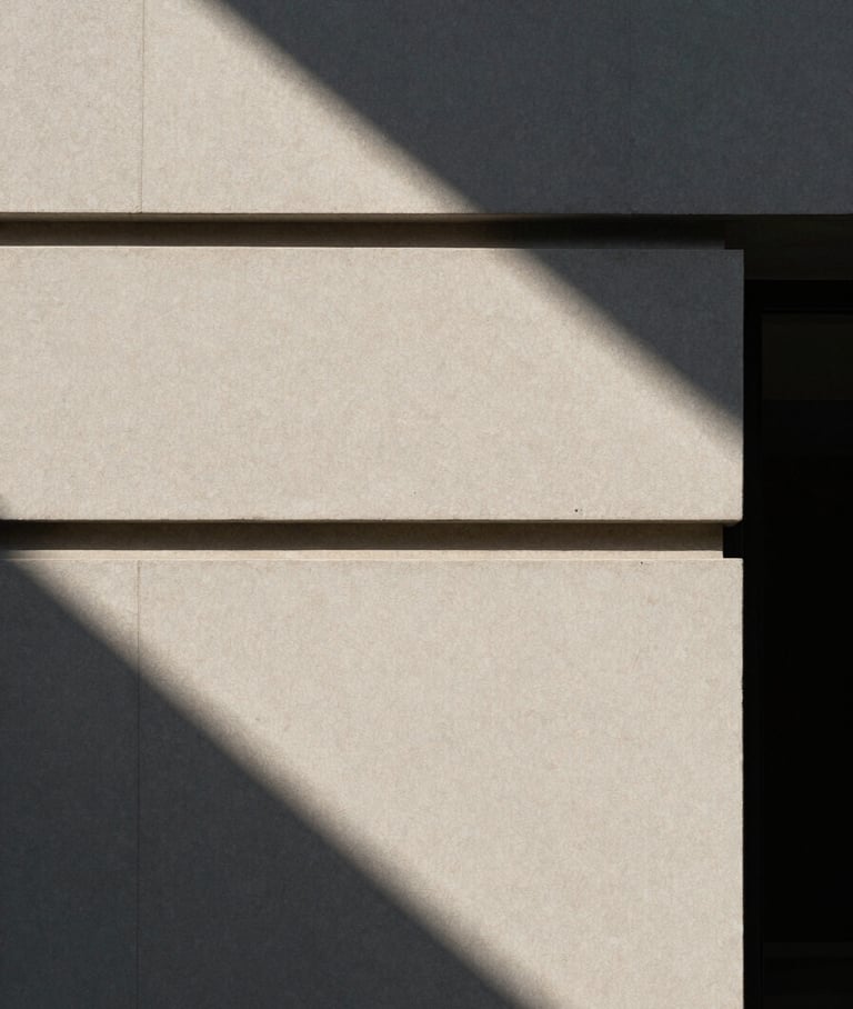 Architectural detail of a minimalist venue facade, harsh direct sunlight casting sharp diagonal shadows.