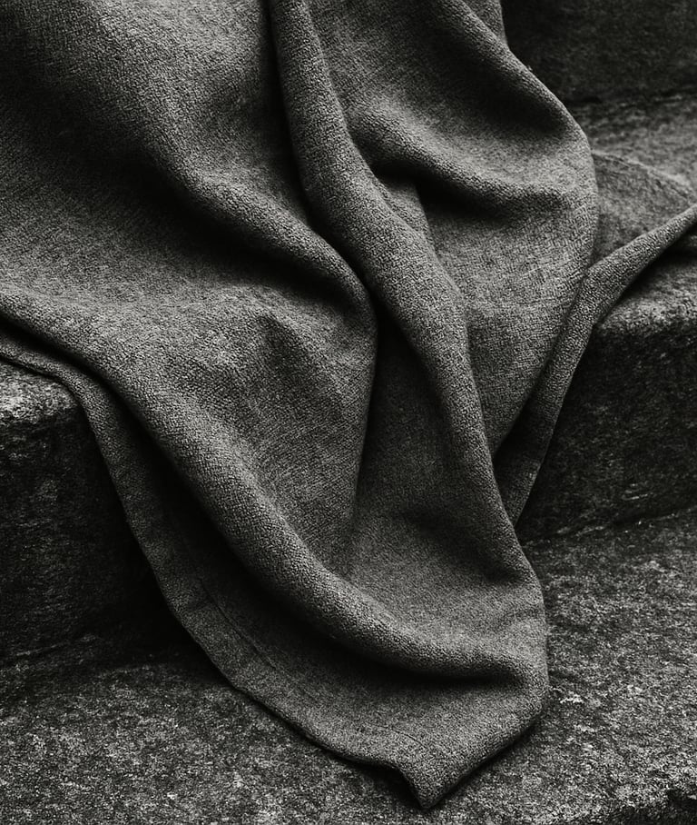 Close-up of heavy gray cotton fabric draped over a textured concrete step, overcast daylight, high contrast, 35mm film