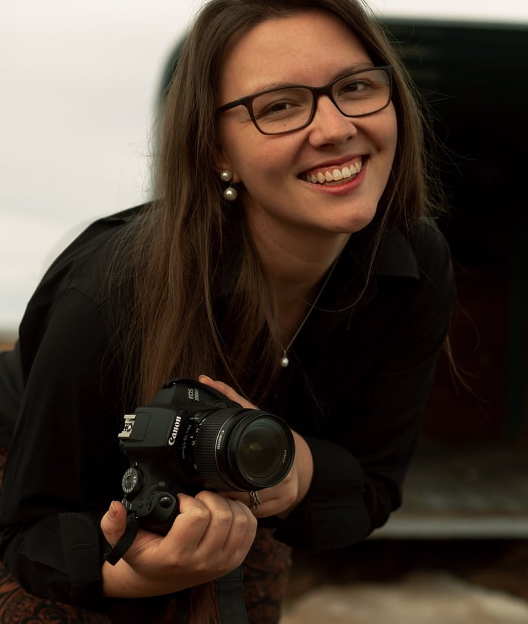 a woman in glasses and a black shirt is holding a camera
