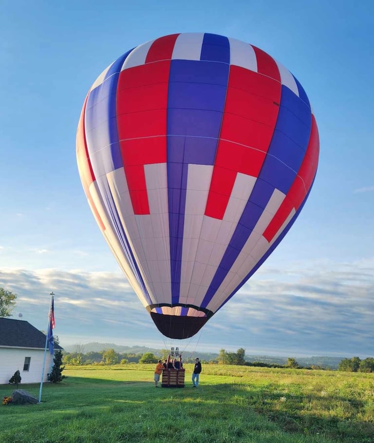 a hot air balloon in a field with people standing around