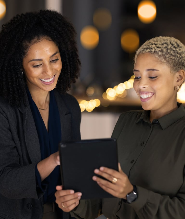 two happy customers standing in front of a table with a tablet