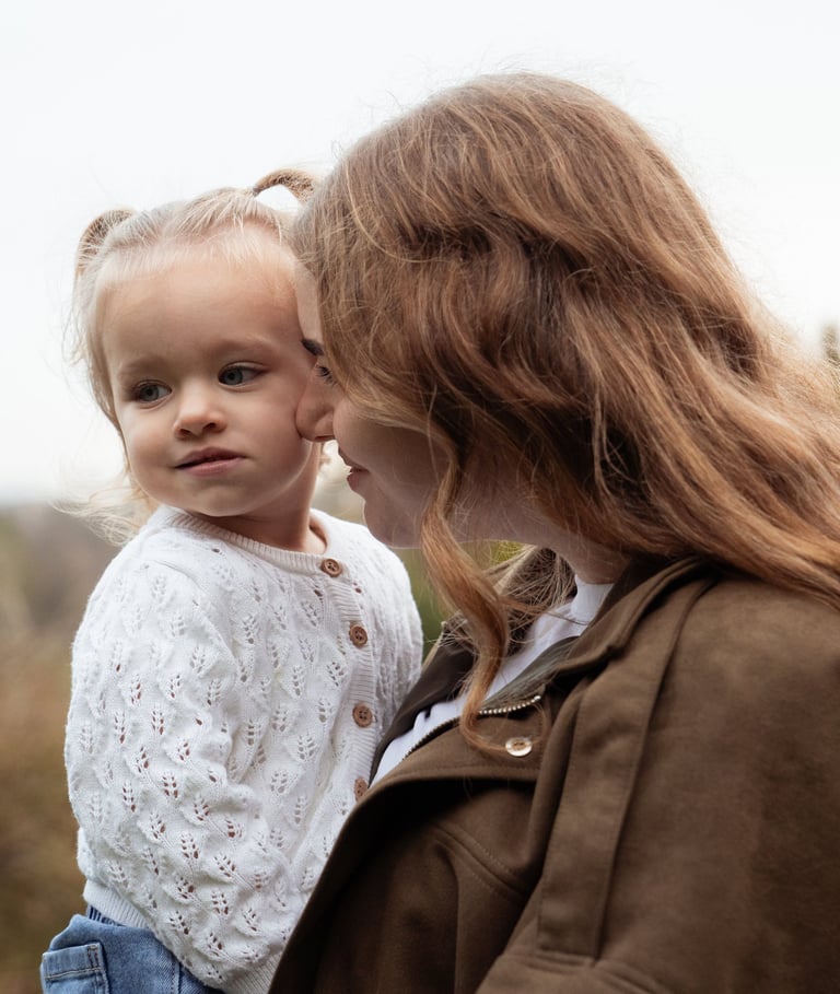 mother holding her daughter on the arms and smiling