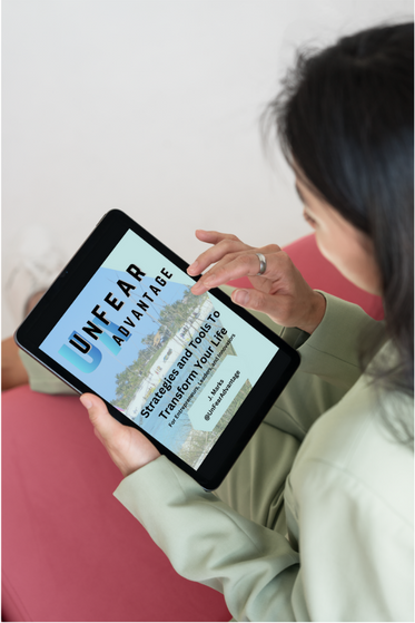 a woman holding a tablet computer and looking at a book called UnFear Advantage