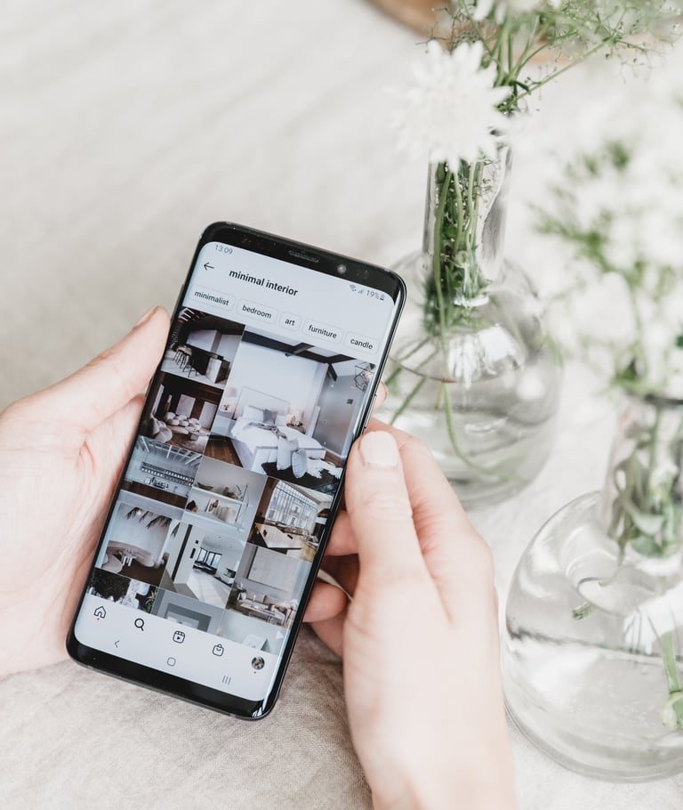 a person holding a phone with a camera and a vase with flowers