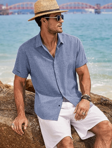 a man in a hat and sunglasses sitting on a rock