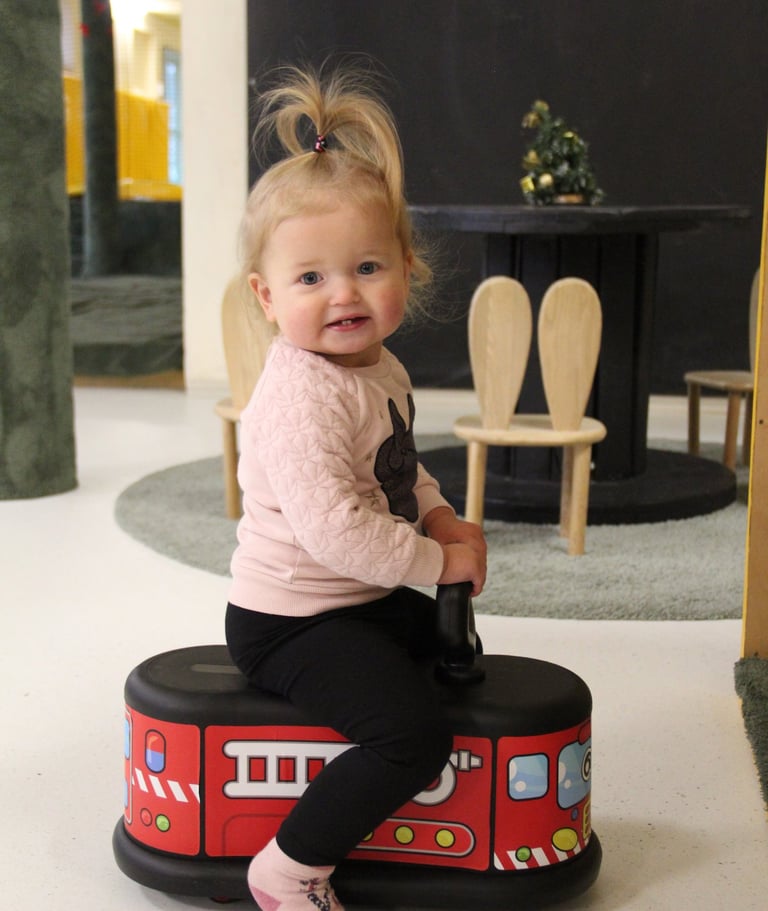 mergaite sėdi ir žaidžia su paspiriama mašinėle