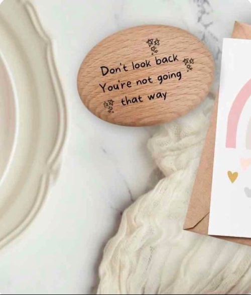 A wooden positivity pebble on a table with a positive card