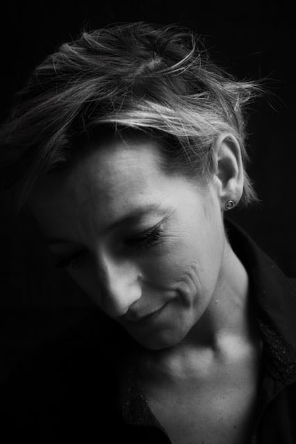 Black and white portrait of a woman with short hair looking down in deep thought.