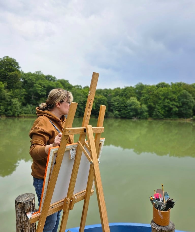 Severine Bugna en train de peindre au bord d'un étang