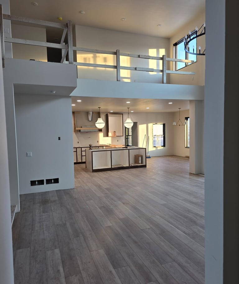 Modern open concept kitchen and living area with luxury vinyl plank flooring and mezzanine balcony.