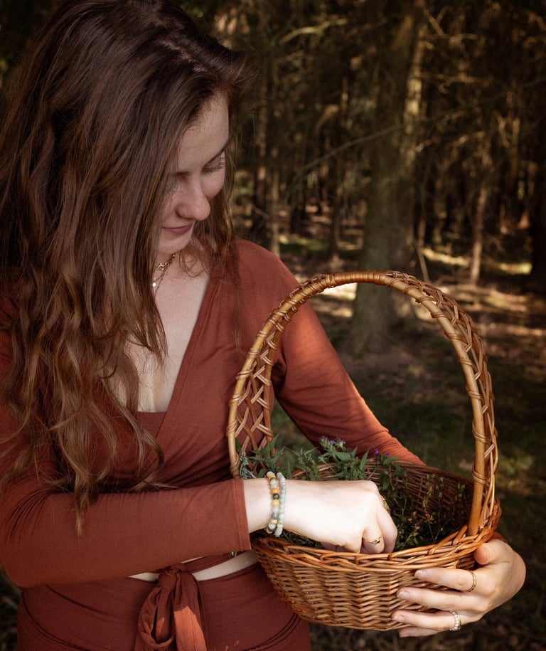 Eine Frau sammelt Kräuter in einem Korb, während sie in einem Wald steht.