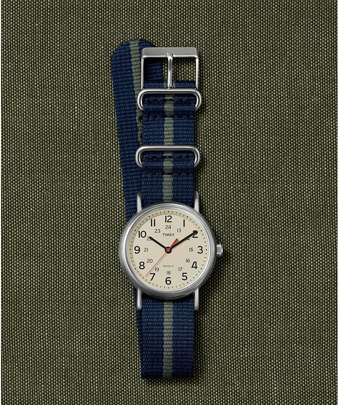 Timex Weekender watch with a blue and grey nylon NATO strap on a green canvas background.