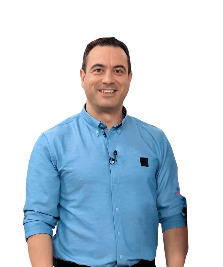 Smiling man in a blue button-down shirt posing against a black background for a professional headshot.