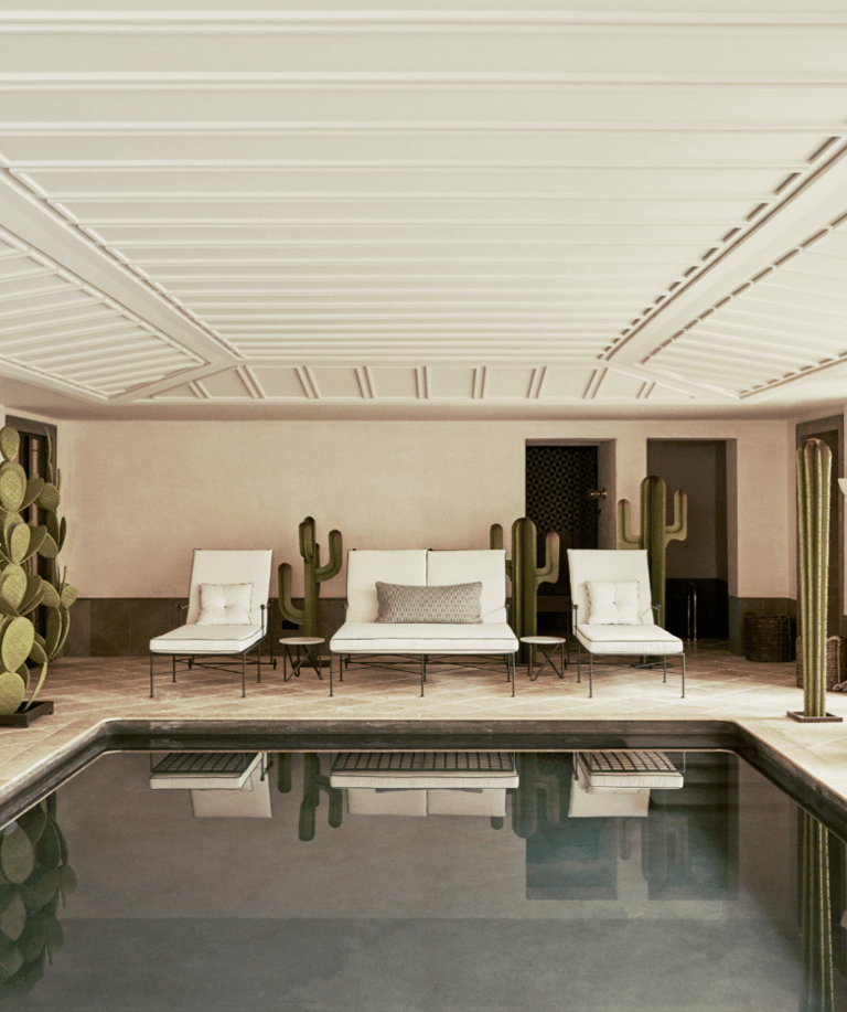 Indoor heated pool at Villa La Gratitud, with lounge beds, potted palms, and garden views beyond.