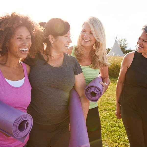a group of women holding yoga mats and smiling