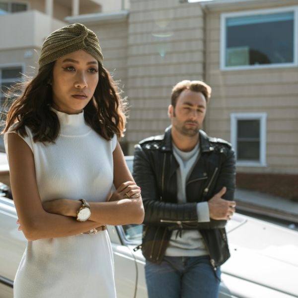 a man and woman standing in front of a car