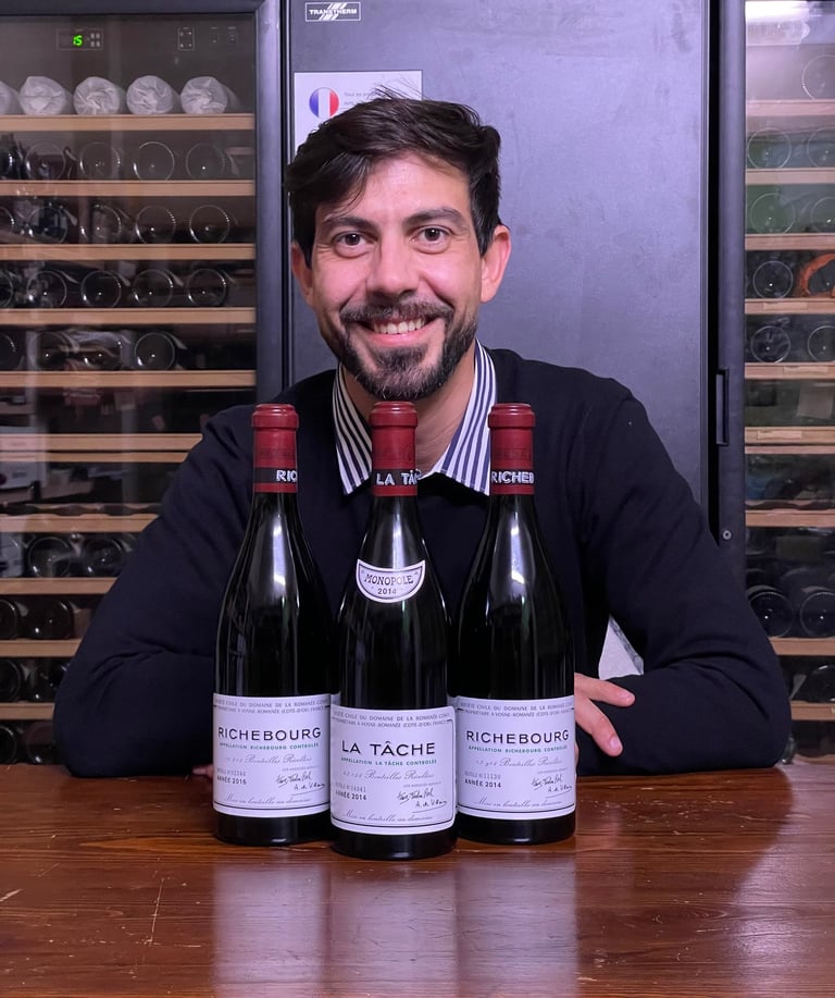 Stefano Cassarino seduto davanti a 3 bottiglie del Domaine de la Romanée Conti