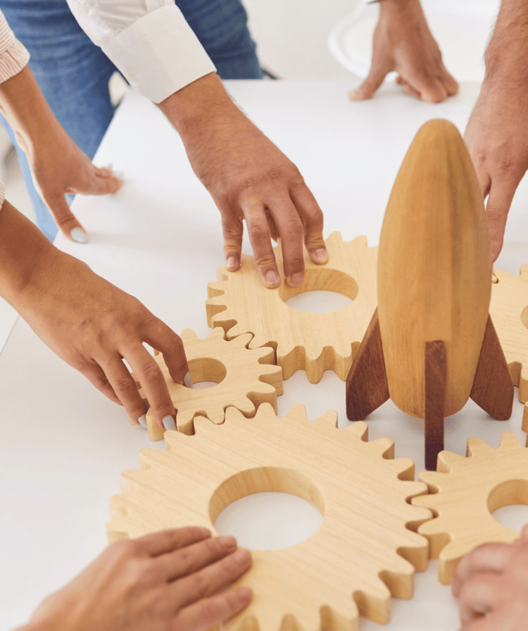 a group of people standing around a table with wooden gear