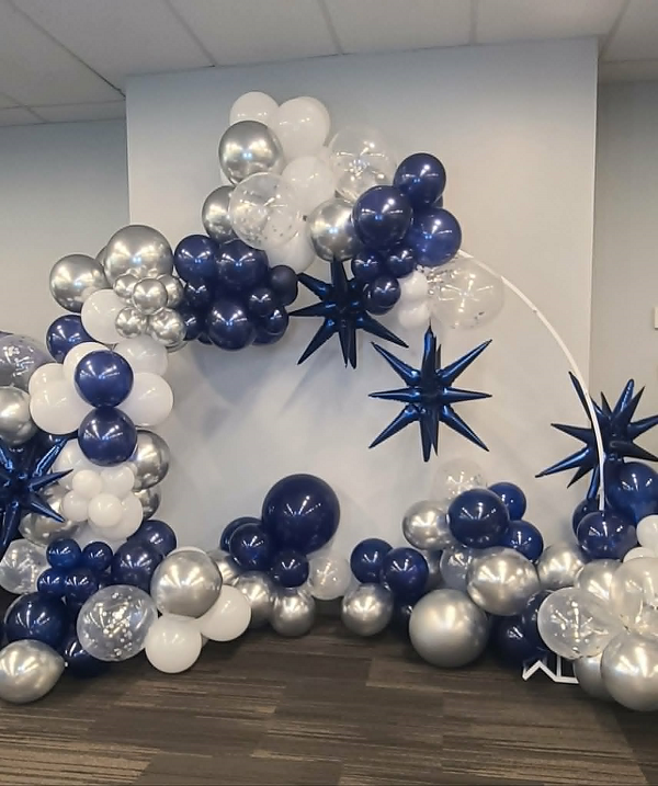 Elegant navy blue, silver, and white balloon garland arch with starburst accents for event decor.