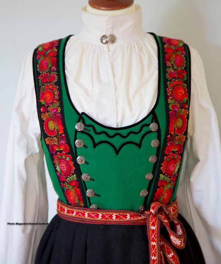 A green bodice bunad with rose embroidery on a mannequin