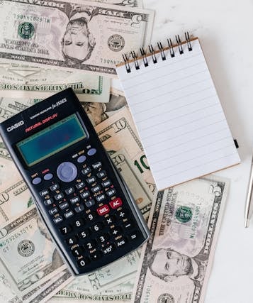 calculator, money, pen, and paper representing making a budget and overall planning finances