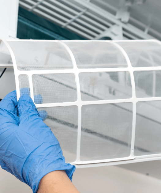 Una persona con guantes sosteniendo un filtro de aire acondicionado