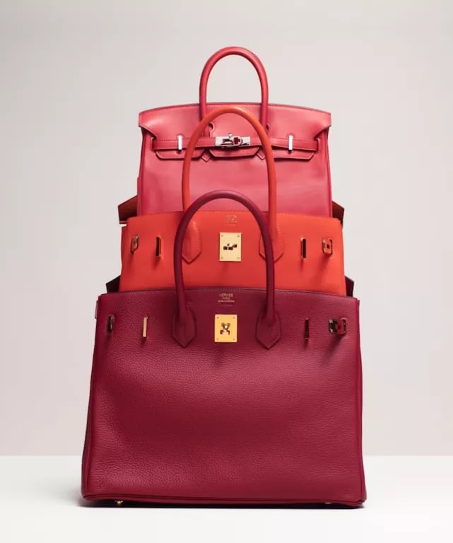 Stacked red and orange luxury Hermes birkin handbags showcasing premium leather craftsmanship.