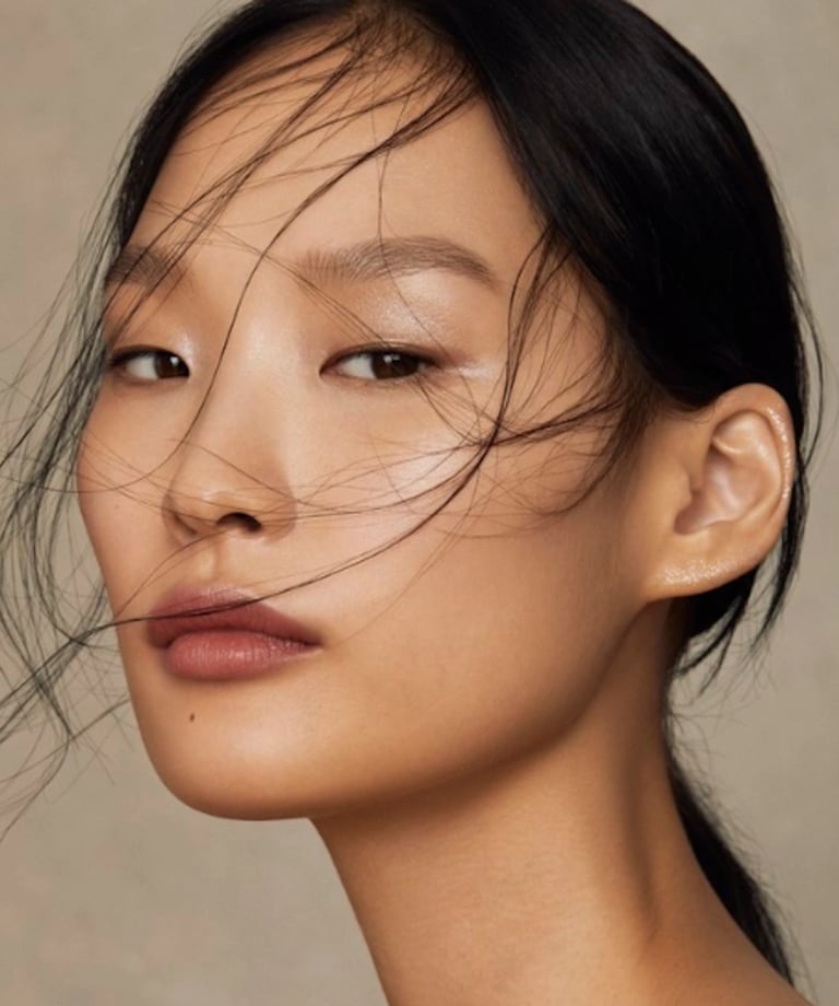 Close-up portrait of an Asian woman with clear skin and natural makeup looking at camera.