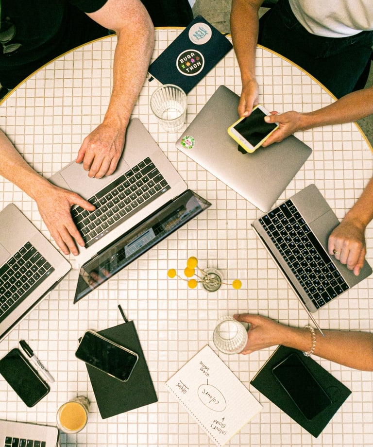 a group of people sitting around a table with laptops