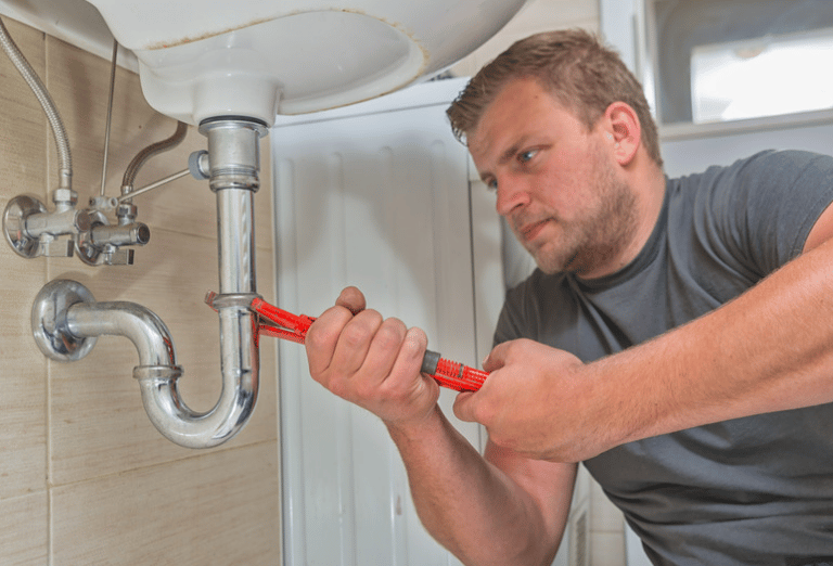 a plumber in a gray shirt is holding a wrench