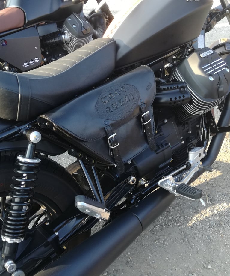 Borsa per moto nera con logo Guzzi di MaxCuoio. Ha due cinghie sul fronte, agganciata al lato di una moto Guzzi