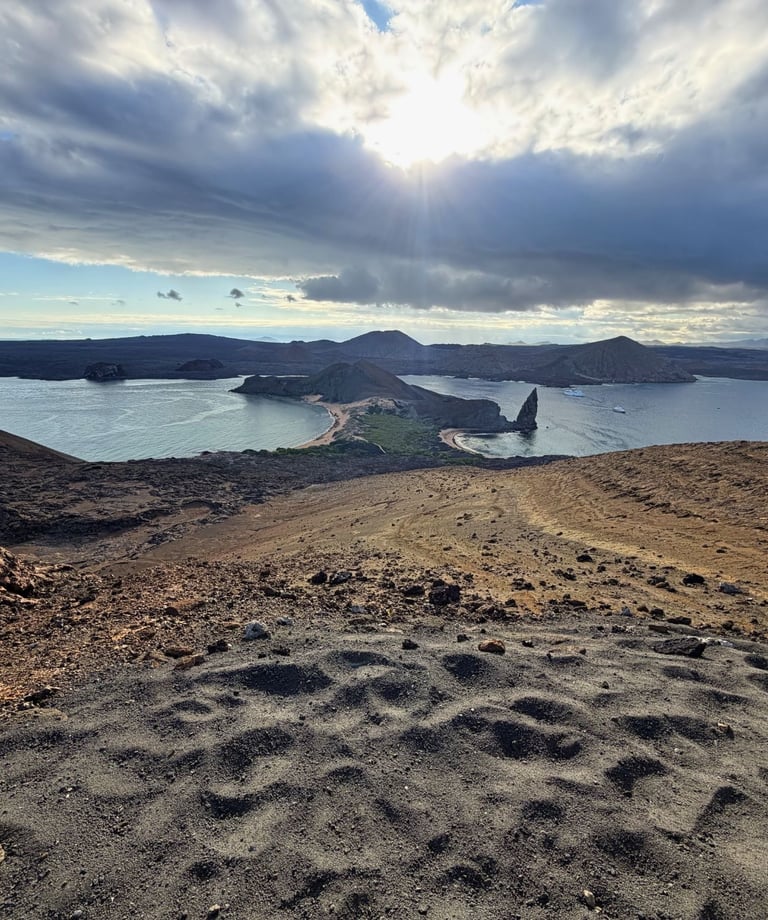 Panoramic view of Bartolome Island and Pinnacle Rock in the Galapagos Islands under a cloudy sky.
