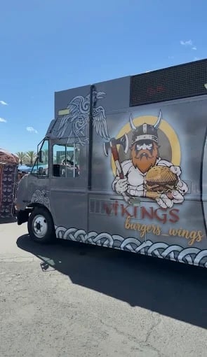 A grey Viking Burgers and Wings food truck featuring a mascot holding an axe and a hamburger.