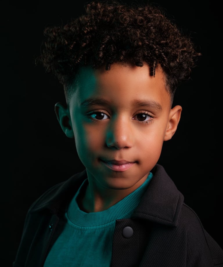 Creatief portret van een jongen van 6 jaar met ondeugende glimlach, in studiolicht met kleuren gels