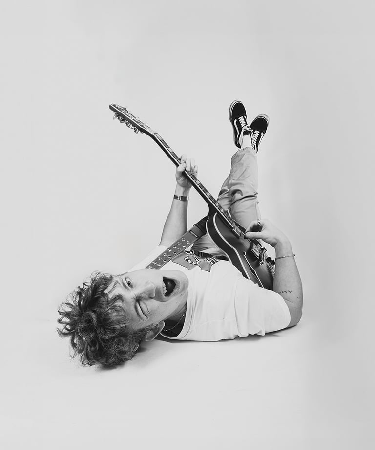 Portret in fashion-editorial stijl met speelse pose, opvallende accessoires en neutrale achtergrond