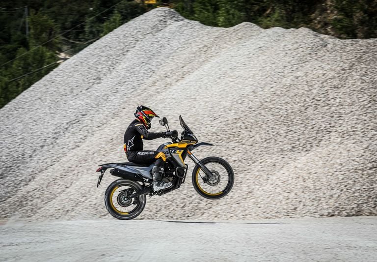 asmuo, važiuojantis motociklu žvyrkeliu