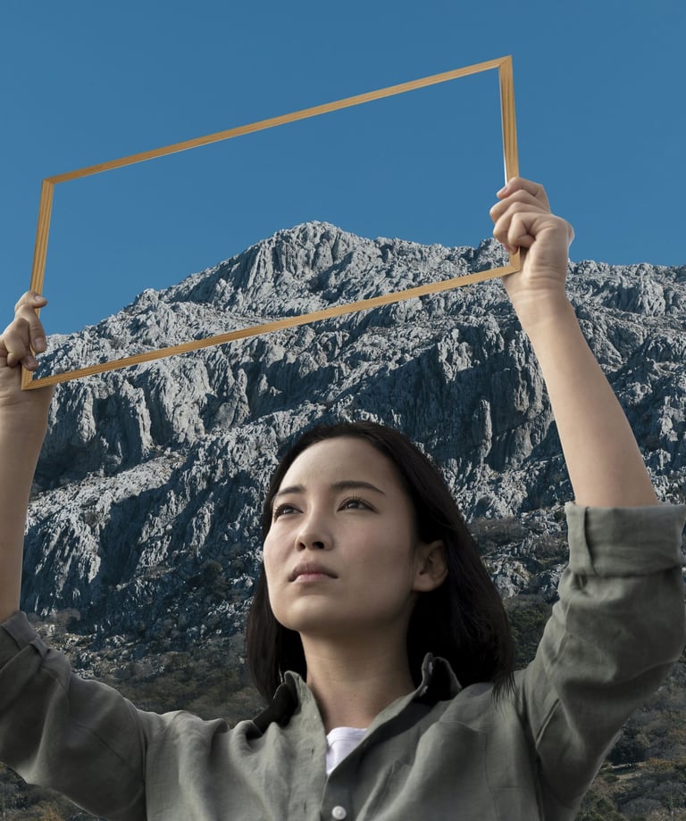 a woman holding a picture frame in front of a mountain