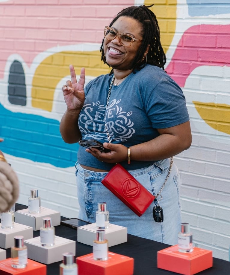 a woman standing in front of a table with a lot of perfumes