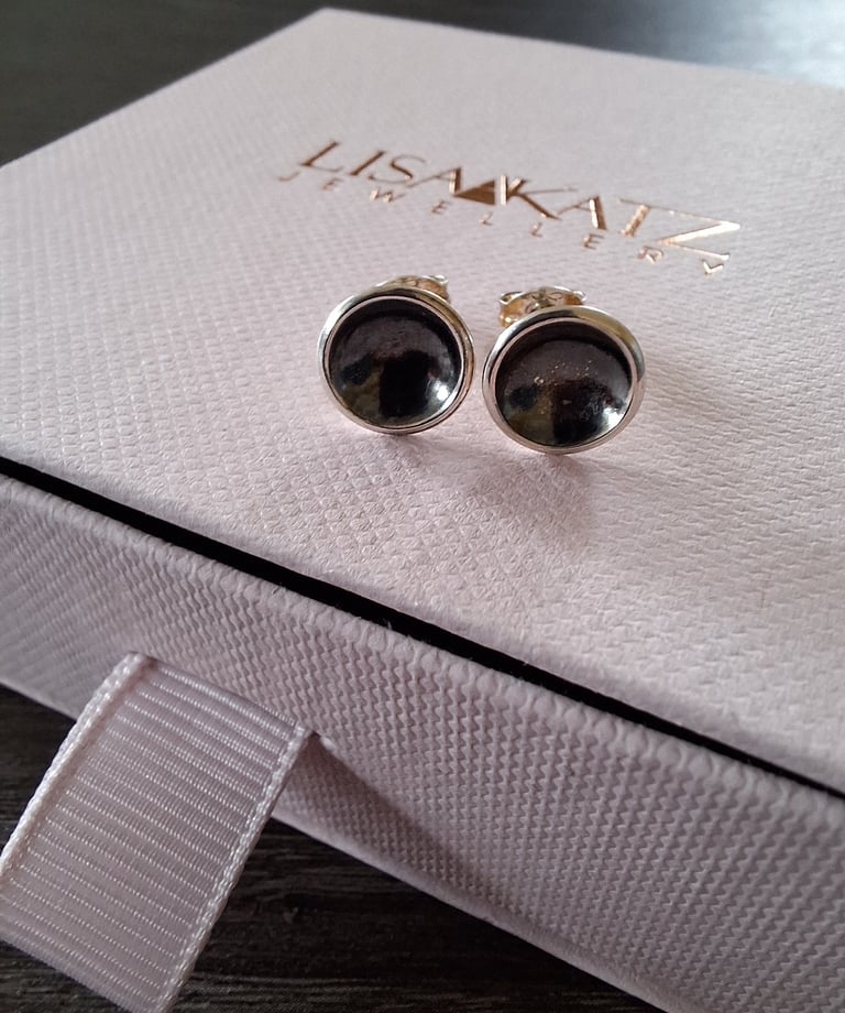 Handmade silver and dark gemstone stud earrings displayed on a pink Lisa Katz Jewellery box.