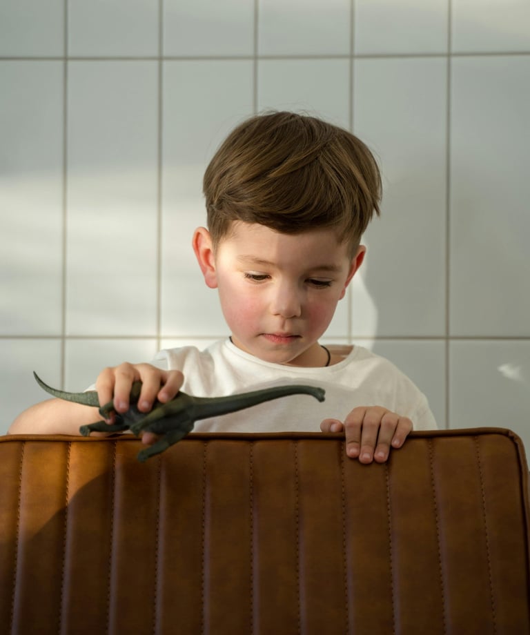 a young boy sitting in a suitcase with a dinosaur toy