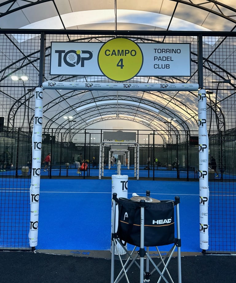 Indoor blue turf padel court at Torrino Padel Club with Head ball basket in the foreground.
