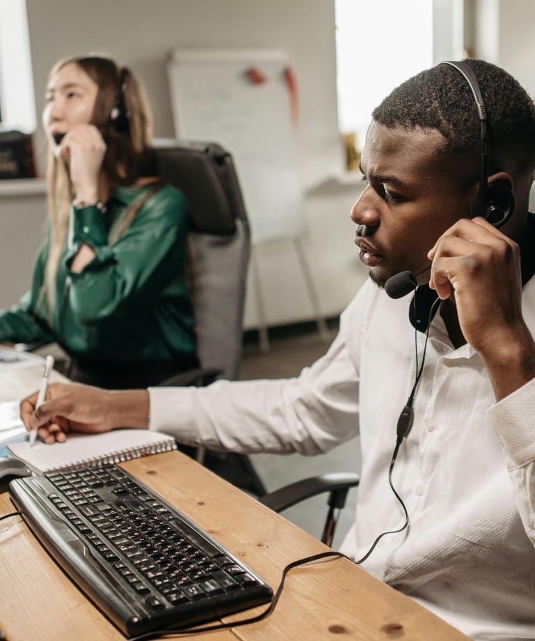 Un homme et une femme assis à un bureau en train d'appeler une autre personne par téléphone