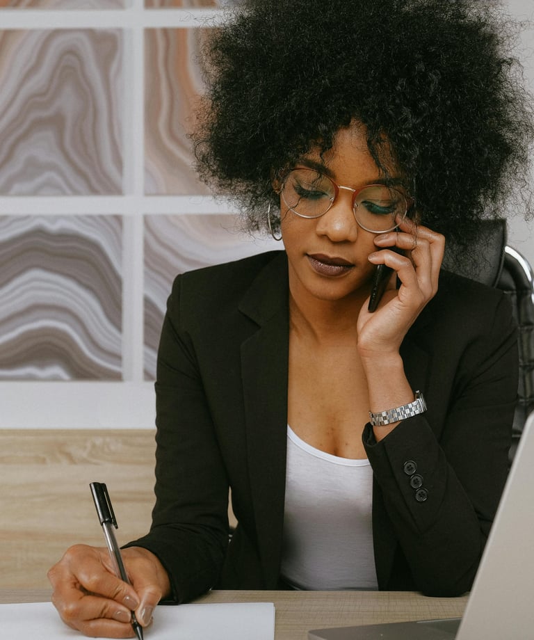 Une femme en tailleur noir et lunettes qui parle au téléphone portable